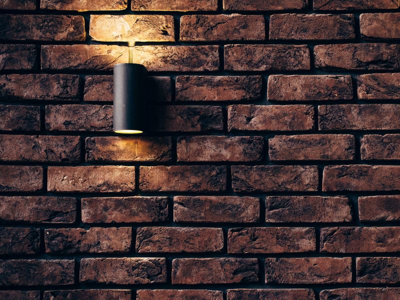 Brown brick exterior wall with lit black cylinder light