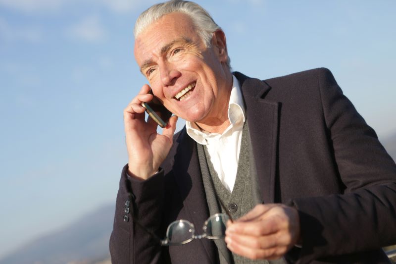 Older male on phone with glasses in hand