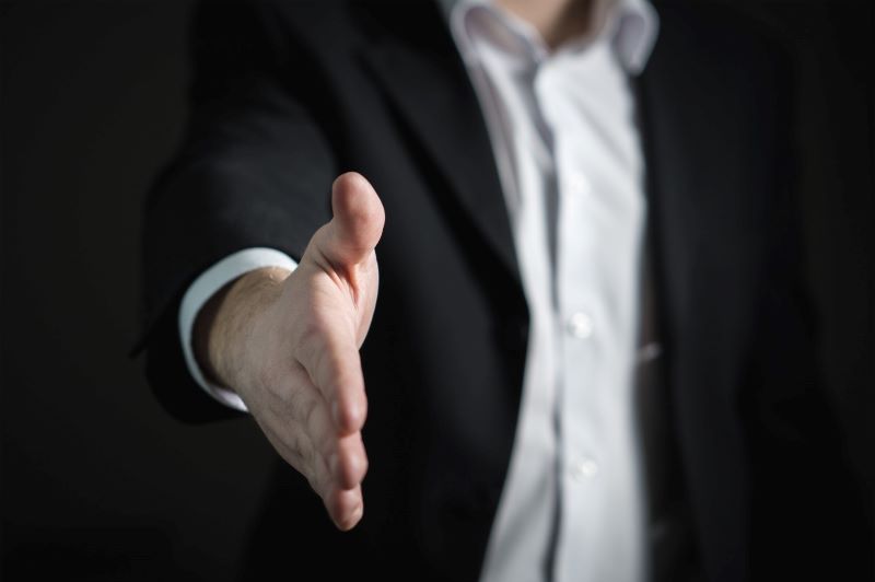 Male real estate agent extending right arm to shake hands